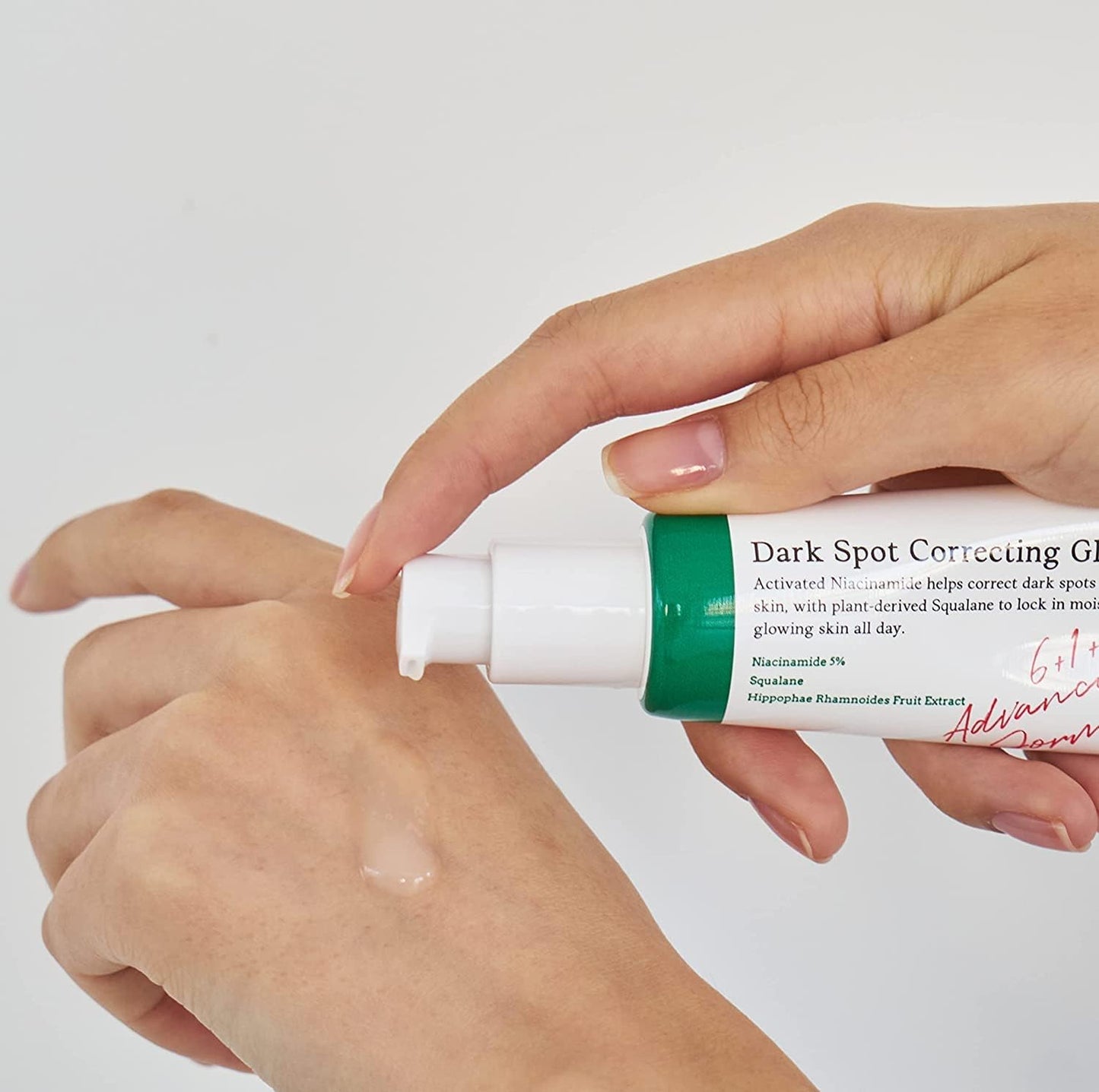 Hand applying dark spot correcting cream to another hand with a white background