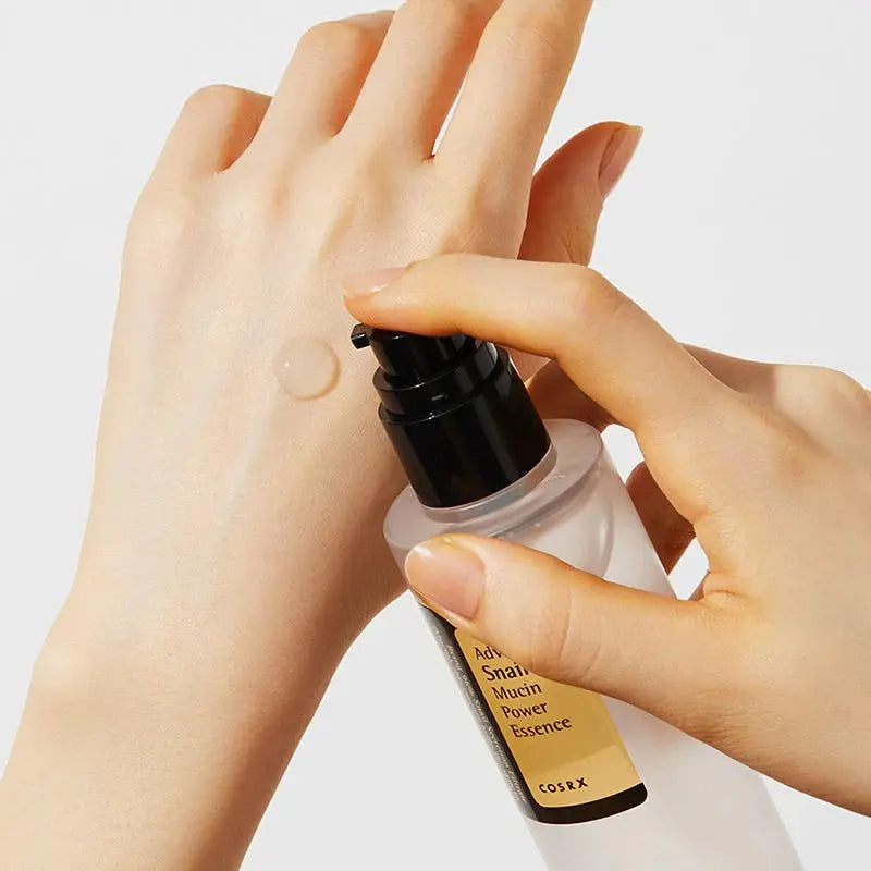 Hand applying COSRX essence to skin with a white background