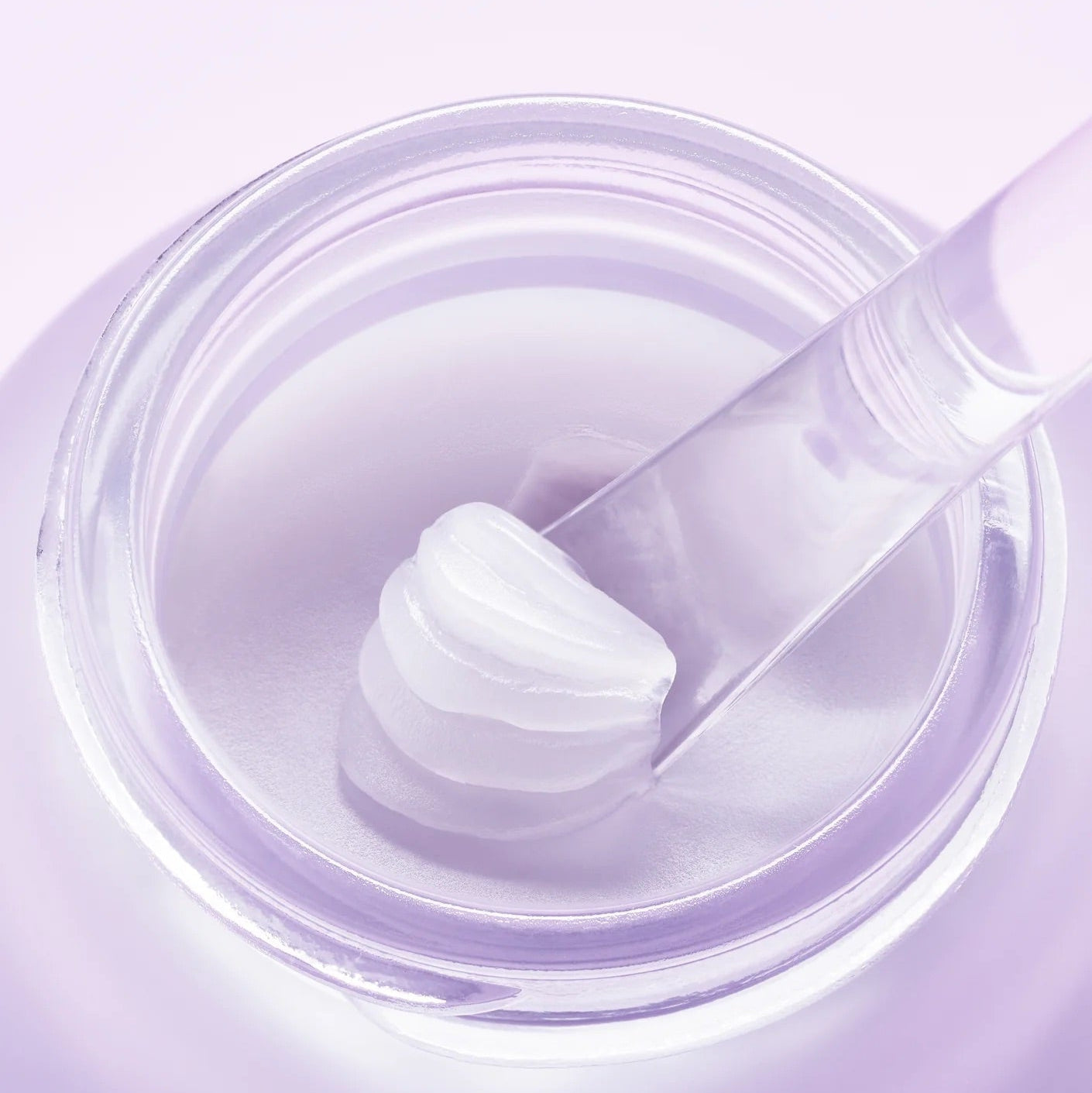 Close-up of a jar of purple cream with a applicator on a matching purple background