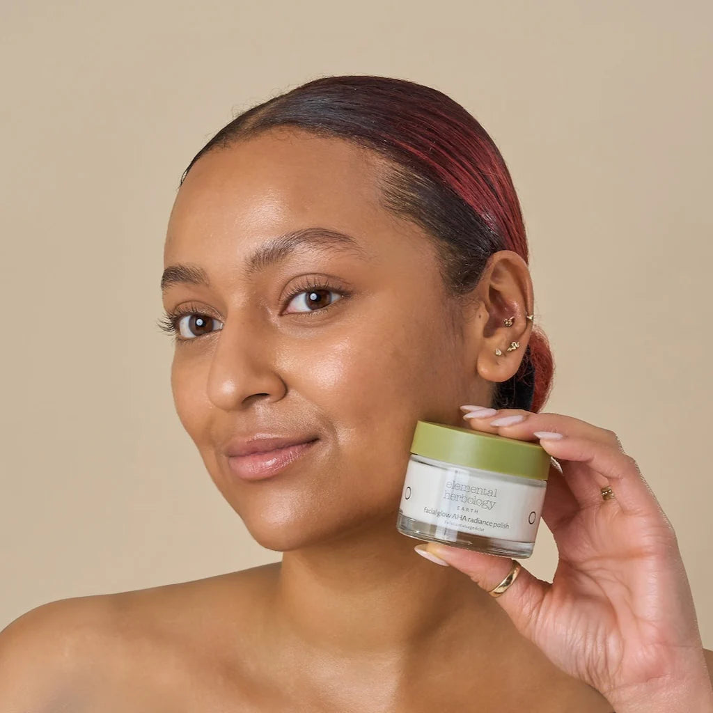 Woman holding a green skincare jar against a beige background