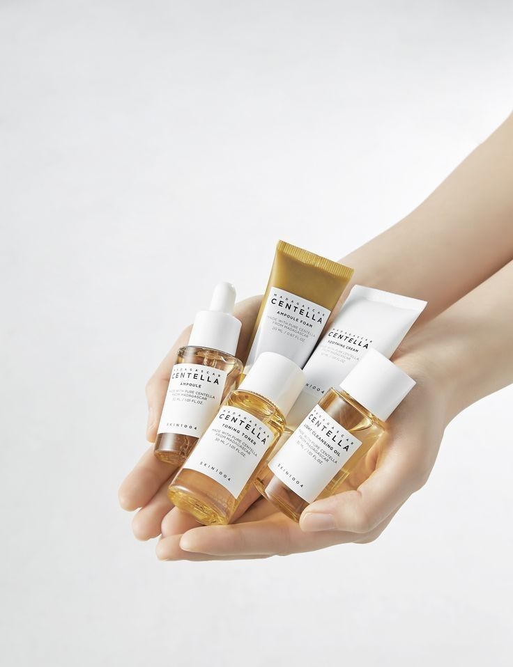 Hand holding Centella Asiatica skincare products on a light gray background