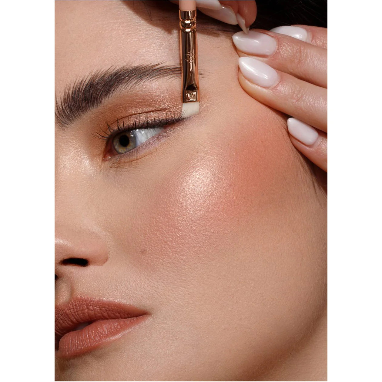 Close-up of a person applying makeup with a brush to their face.