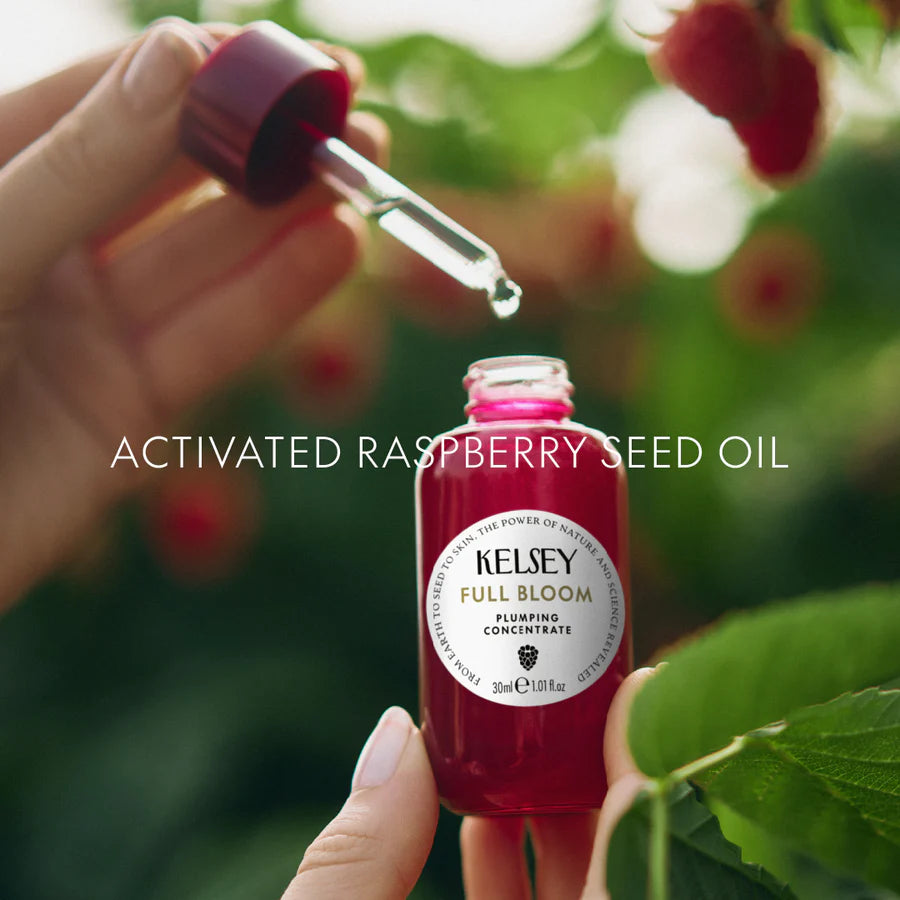 Bottle of Kelsey Full Bloom Activated Raspberry Seed Oil with a dropper over raspberries.