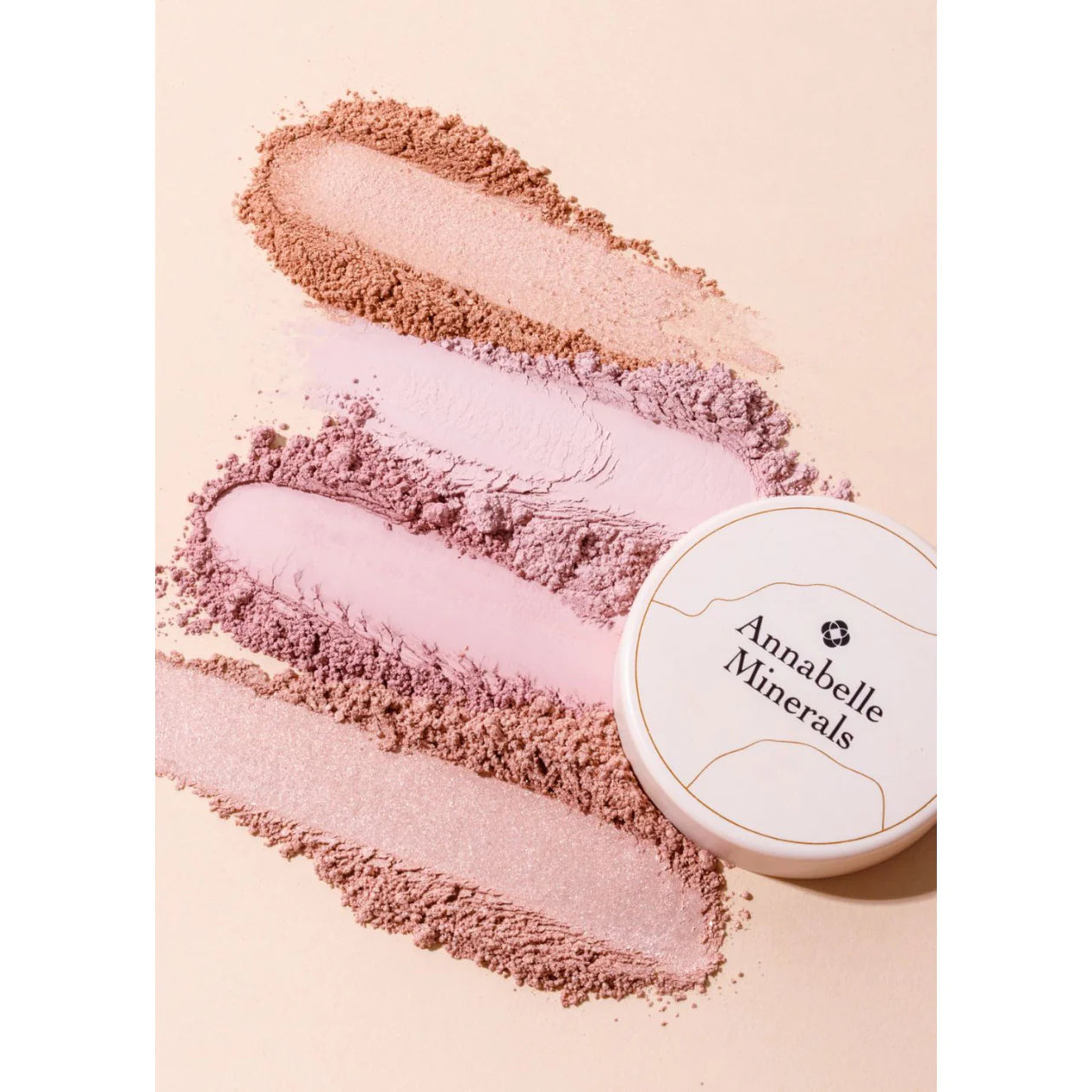 Mineral makeup powders in various shades with 'Annabelle Minerals' container on a light pink background