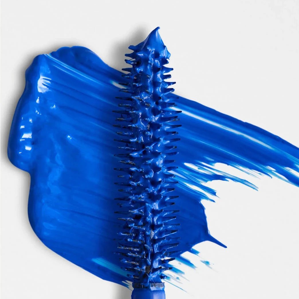 Blue hairbrush with bristles against a blue paint-like background