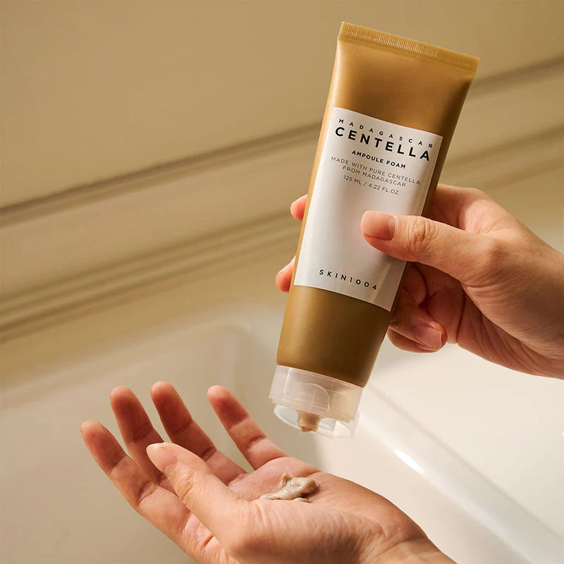 Hand holding a tube of Skinfood Madagascar Centella Astringent Foam over another hand with foam on palm.