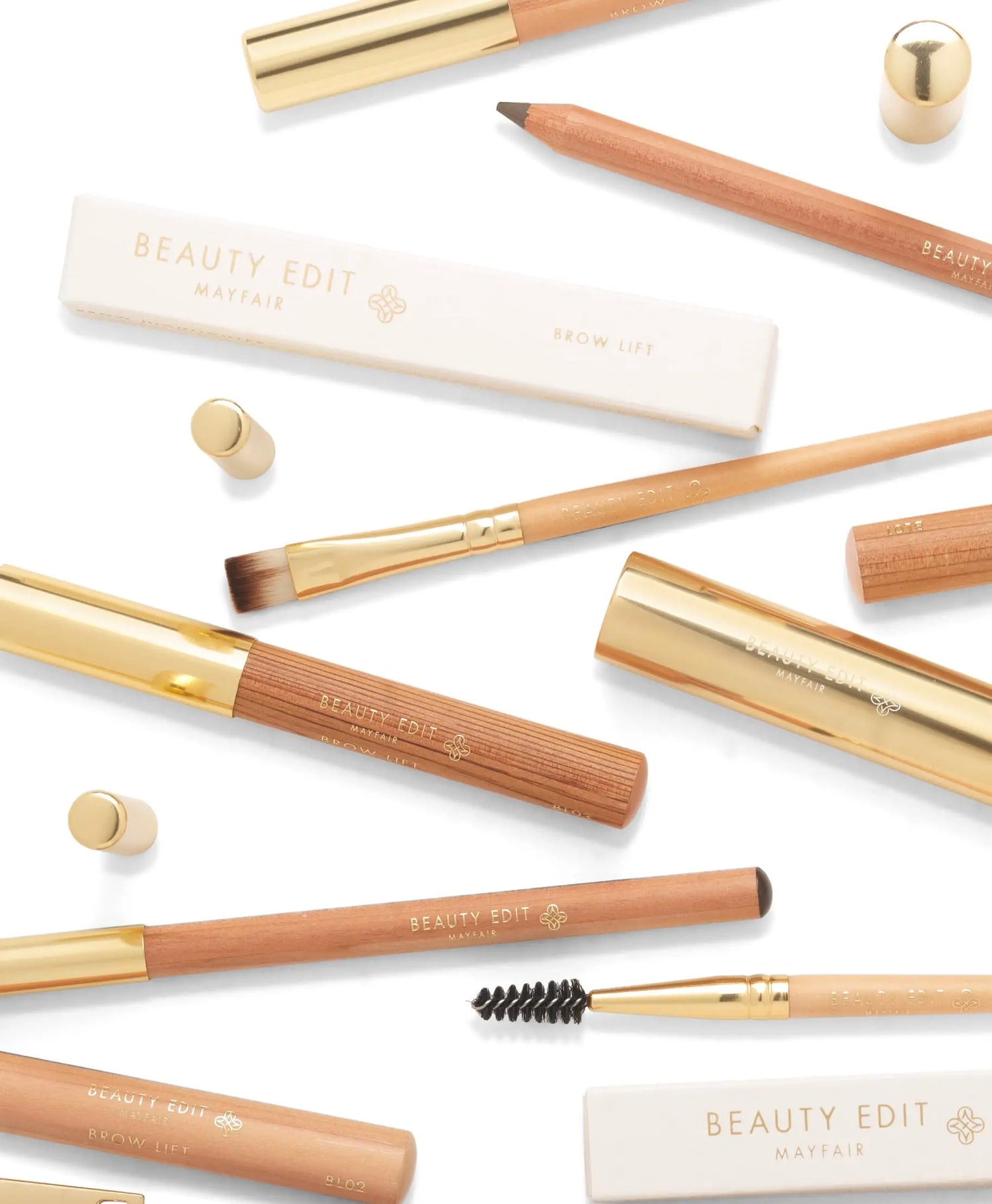 Looking staight down on Beauty Edit Mayfair brushes and pencils, boxed and otherwise, laid on a white table top