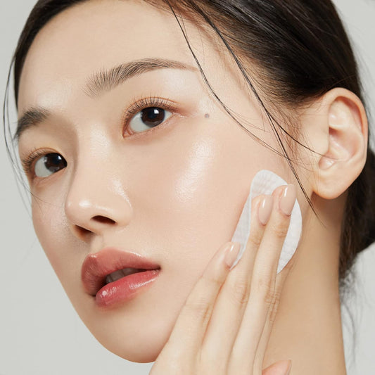 Woman applying cream to her face with a neutral background