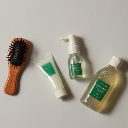 Set of hair care products including a brush, tube, spray bottle, and bottle on a neutral background.