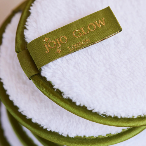 Green and white makeup pad with 'Jojo Glow' branding on a blurred background