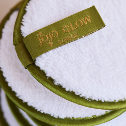 Green and white makeup pad with 'Jojo Glow' branding on a blurred background